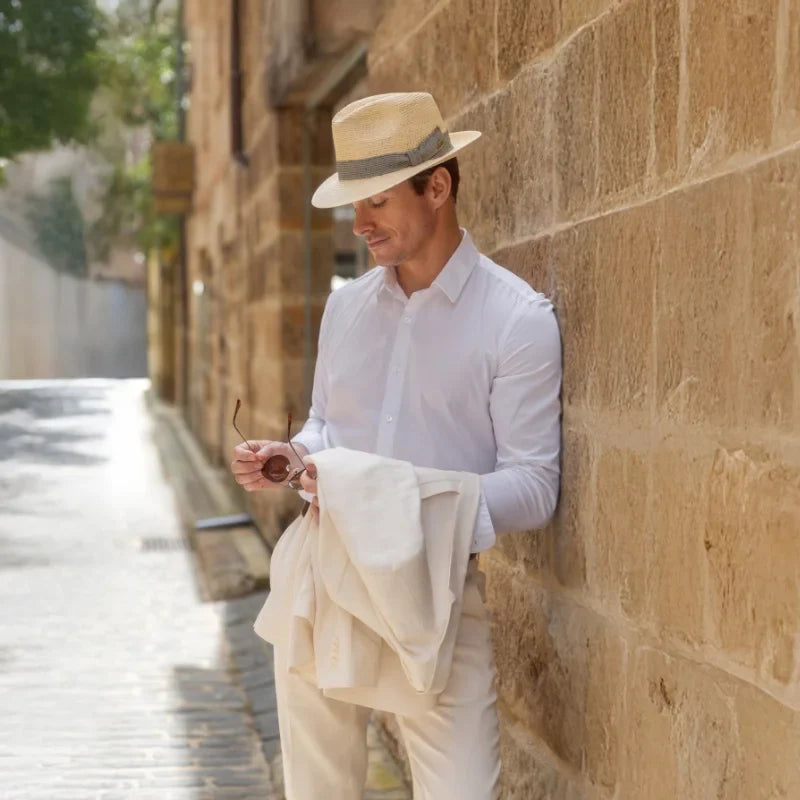 Male Model sitting in front of sandstone wall wearing a traditional Panama Hat