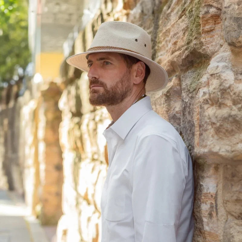 Male model standing in front of white brick wall wearing an outdoor style hat